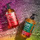 Peppermint-Vanilla and Winter Pine scented hand soap bottles splashing in a water surfaced. Pink to green gradient background.