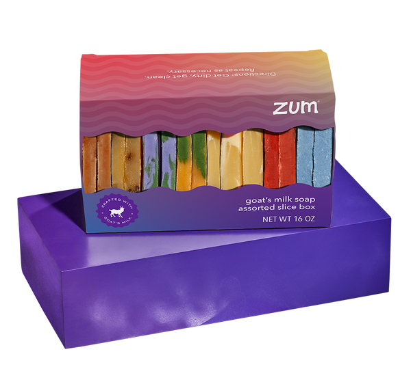 Rectangular shaped box with a wavy cutout filled with slices of assorted scents of bar soaps sitting on a purple block.